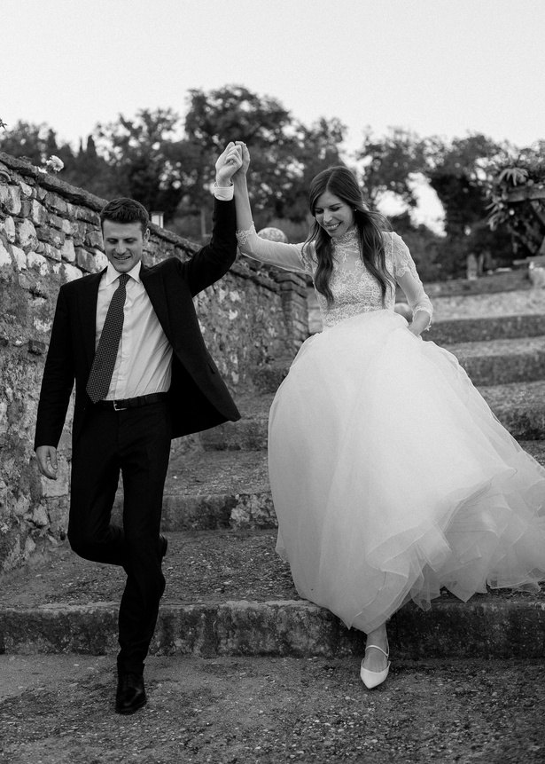 Gli sposi si tengono per mano e scendono di corsa una scalinata di pietra