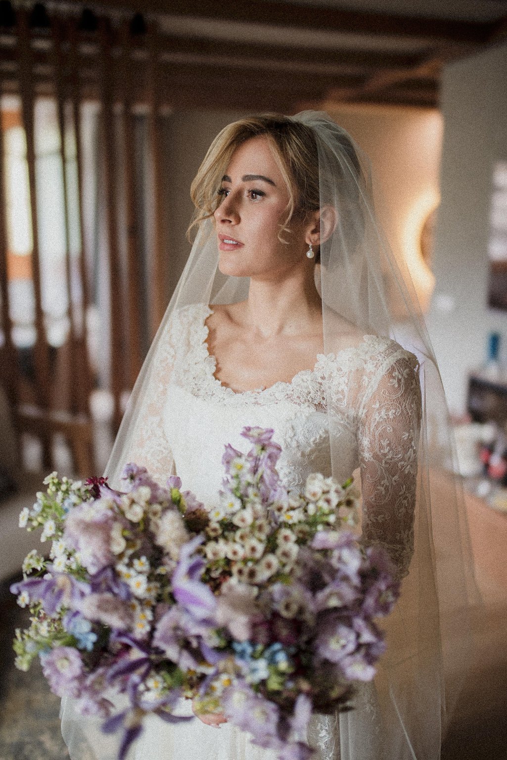 Ritratto della sposa con il velo e un bouquet di fiori lilla